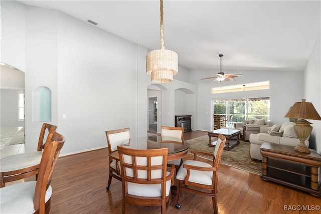 dining space with ceiling fan with notable chandelier, dark hardwood / wood-style flooring, and lofted ceiling