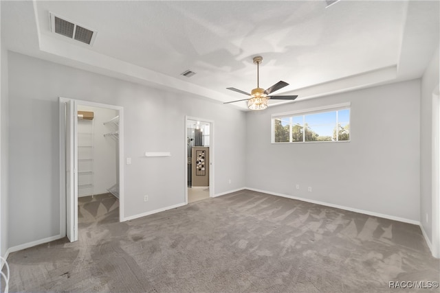 unfurnished bedroom featuring carpet flooring, ceiling fan, a walk in closet, and a closet