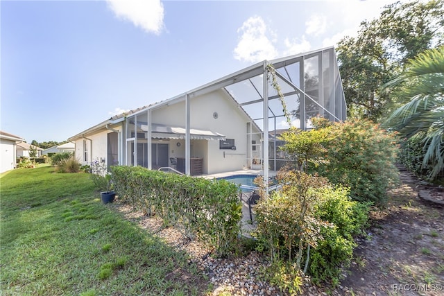 rear view of property with glass enclosure and a yard