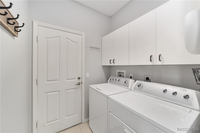 laundry area featuring washer and dryer, cabinets, and light tile patterned floors