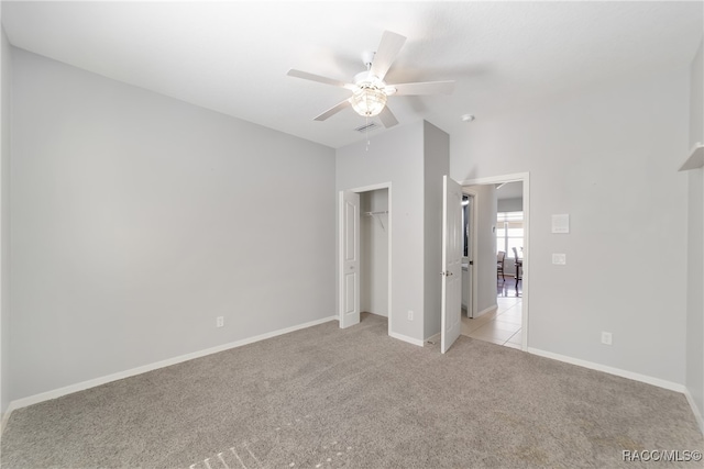 unfurnished bedroom featuring ceiling fan, light colored carpet, lofted ceiling, and a closet