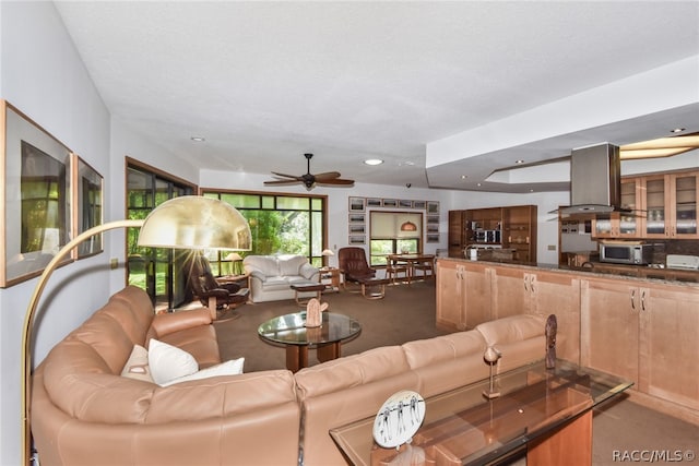 carpeted living room with ceiling fan and a textured ceiling