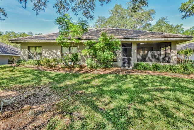 rear view of house featuring a sunroom and a yard