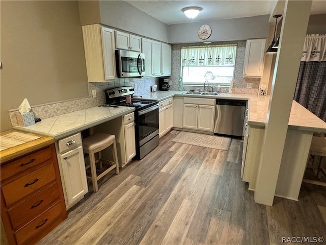 kitchen featuring a breakfast bar area, white cabinetry, sink, and appliances with stainless steel finishes