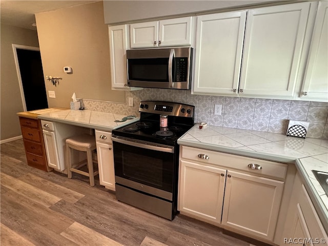 kitchen with white cabinets, light wood-type flooring, and stainless steel appliances