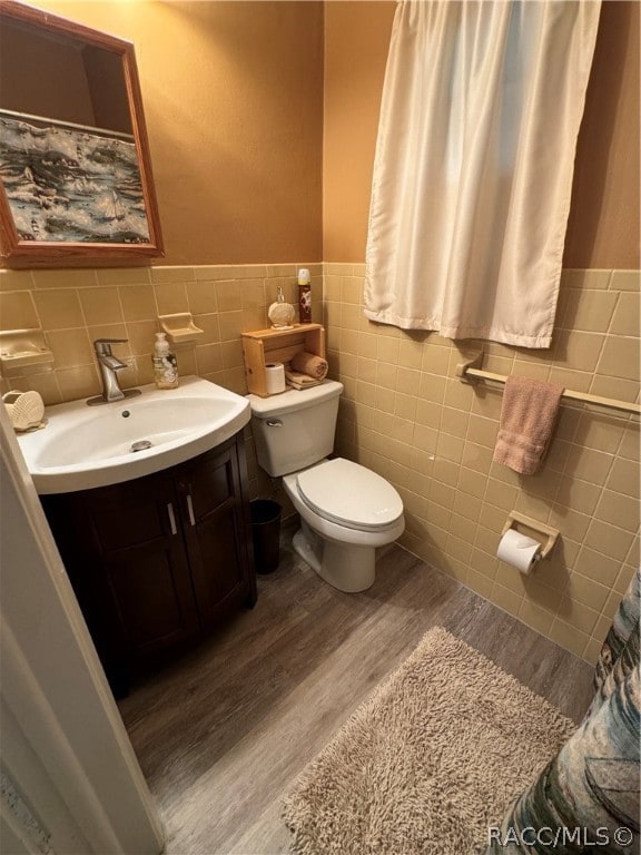 bathroom with hardwood / wood-style flooring, vanity, toilet, and tile walls