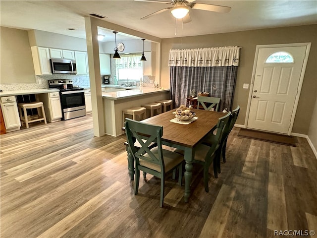 dining space with ceiling fan and light hardwood / wood-style flooring