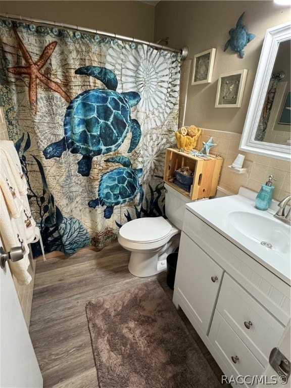 bathroom with hardwood / wood-style floors, vanity, toilet, and tile walls