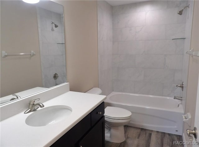 full bathroom with vanity, tiled shower / bath, wood-type flooring, and toilet