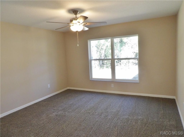 empty room with ceiling fan and dark carpet