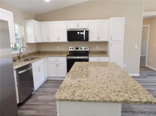 kitchen featuring sink, stainless steel appliances, a kitchen island, vaulted ceiling, and white cabinets