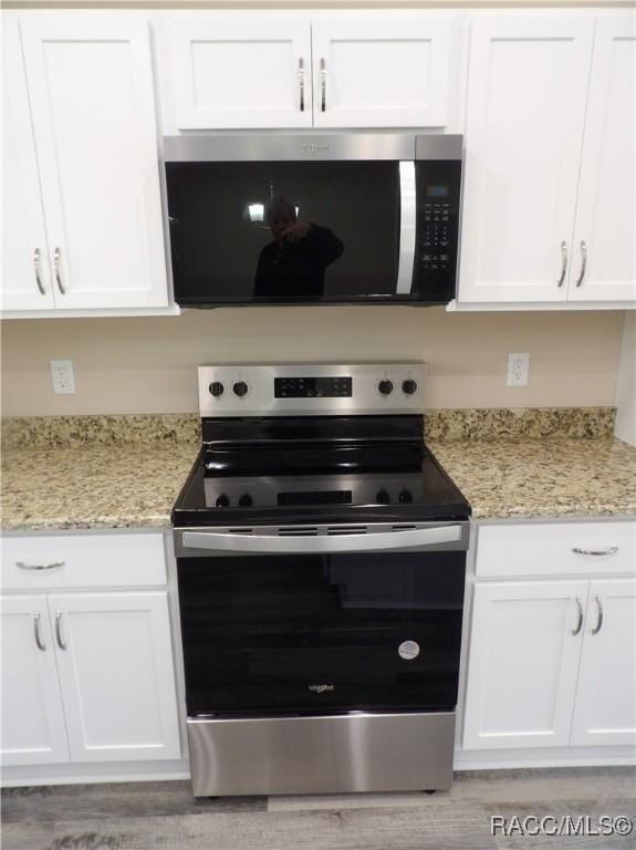 kitchen with light stone countertops, white cabinets, and appliances with stainless steel finishes