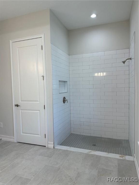 bathroom with tiled shower and tile patterned floors