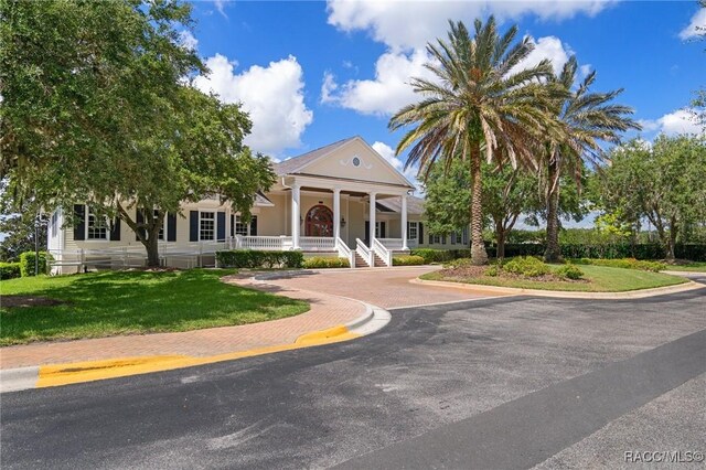 greek revival inspired property with covered porch and a front lawn