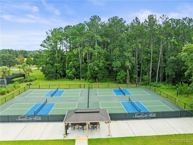 view of tennis court with fence and a view of trees