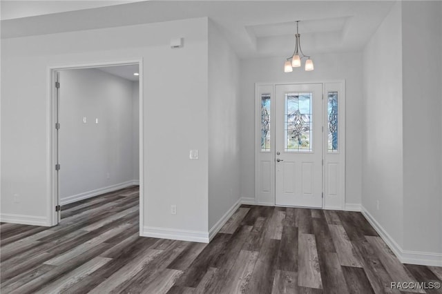 entrance foyer with dark wood-style flooring, a raised ceiling, and baseboards