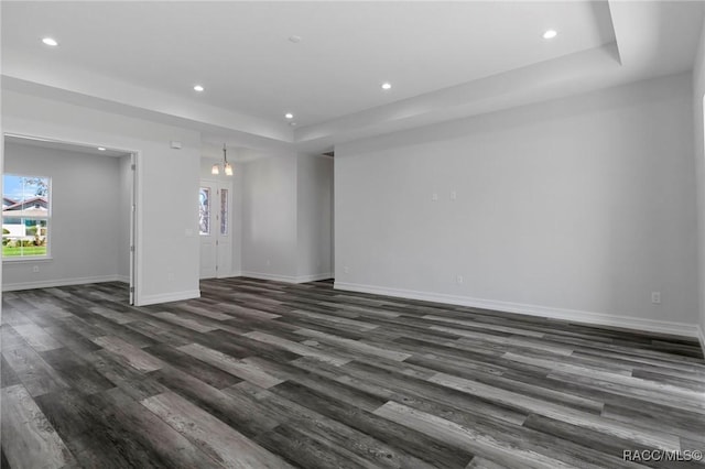 spare room with baseboards, dark wood finished floors, a tray ceiling, and recessed lighting