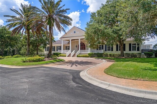 view of front of house with a porch, a front lawn, and decorative driveway