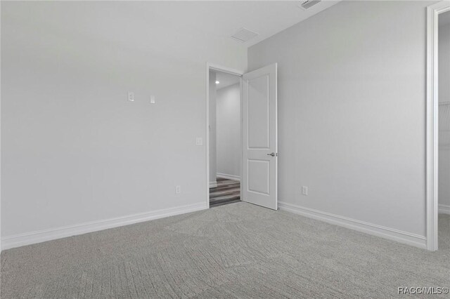 carpeted spare room featuring visible vents and baseboards