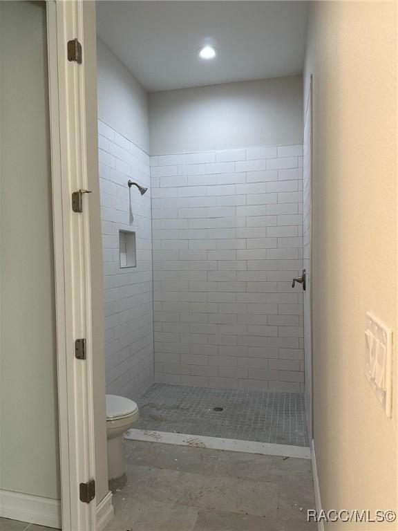 bathroom with toilet and a tile shower