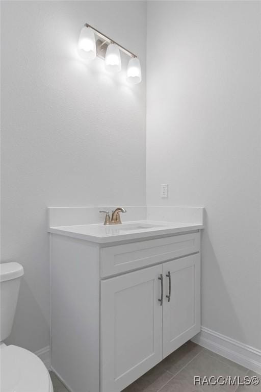 bathroom featuring tile patterned flooring, baseboards, vanity, and toilet