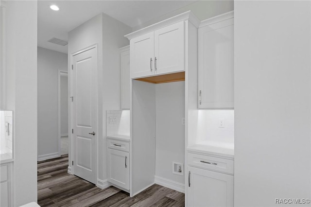 kitchen with visible vents, white cabinets, light countertops, tasteful backsplash, and dark wood finished floors