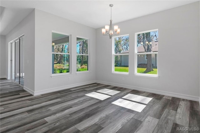 unfurnished dining area with a notable chandelier, wood finished floors, and baseboards