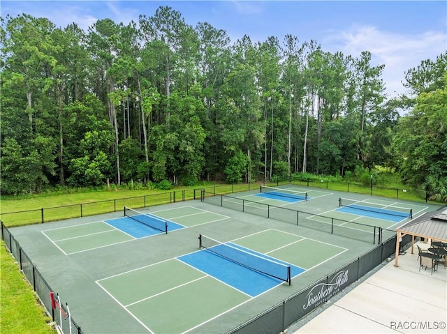 view of tennis court with a lawn and fence