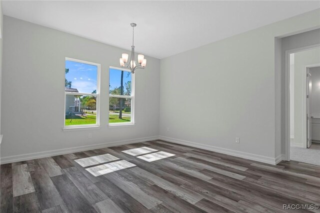 unfurnished dining area featuring a chandelier, wood finished floors, and baseboards