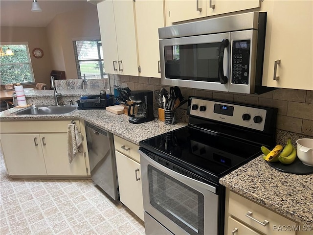 kitchen featuring sink, stainless steel appliances, light stone countertops, and tasteful backsplash