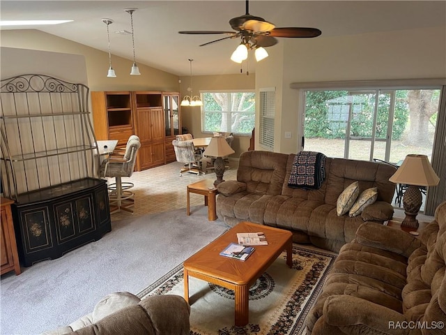 carpeted living room with lofted ceiling, a wealth of natural light, and ceiling fan with notable chandelier