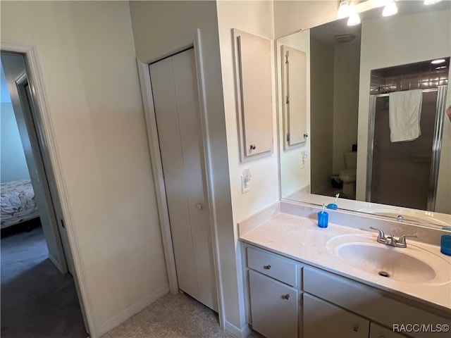 bathroom with a shower with door, vanity, and toilet