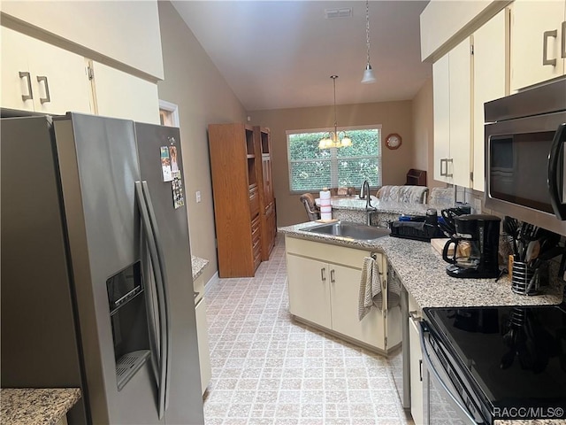 kitchen with vaulted ceiling, decorative light fixtures, an inviting chandelier, appliances with stainless steel finishes, and sink