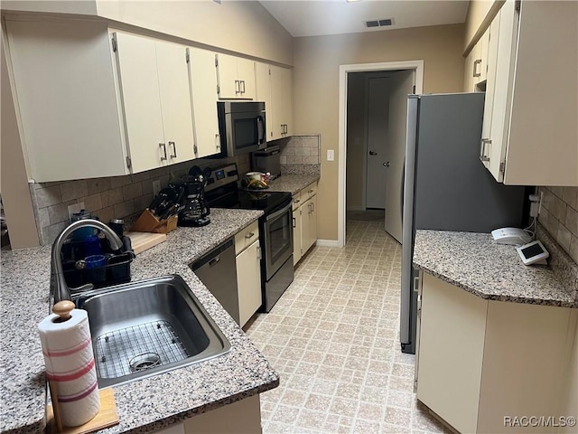 kitchen with stainless steel appliances, sink, light stone counters, lofted ceiling, and decorative backsplash