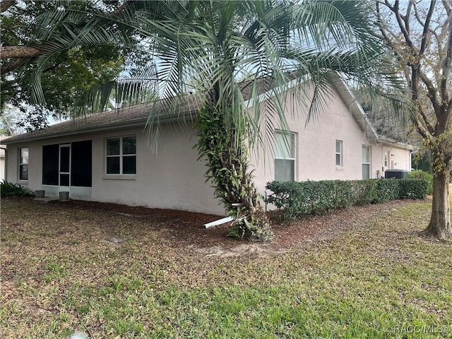 view of property exterior with a yard and central air condition unit