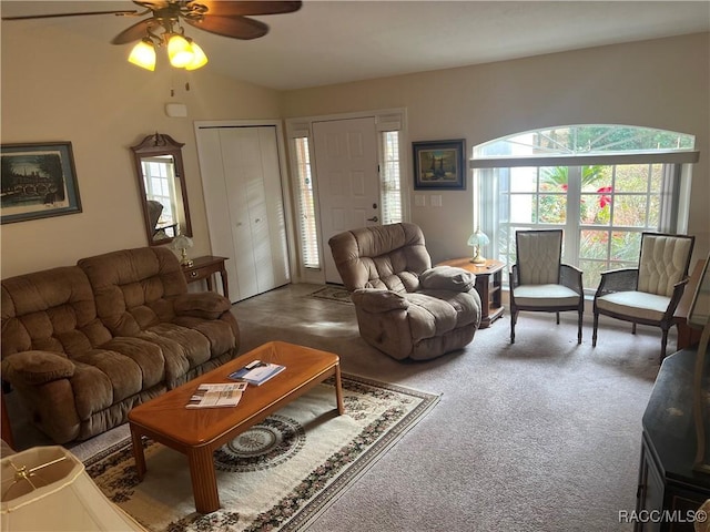 living room with lofted ceiling, ceiling fan, and carpet flooring