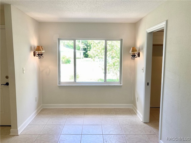 unfurnished room featuring light tile patterned floors and a textured ceiling