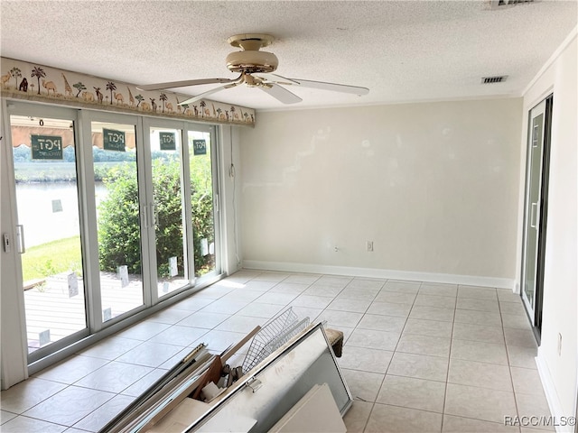 unfurnished room featuring ceiling fan, light tile patterned floors, and a textured ceiling