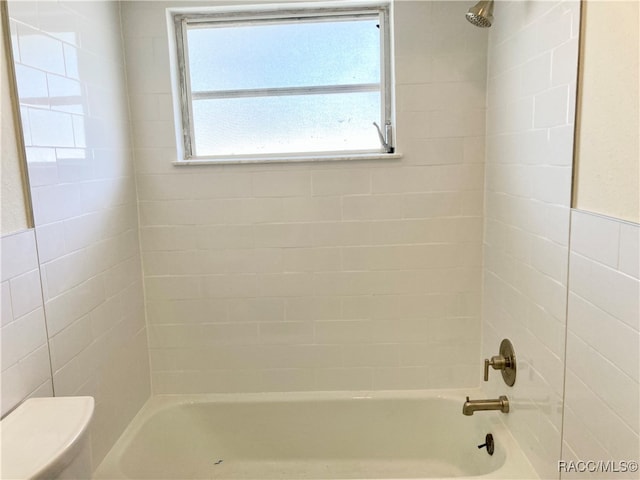 bathroom with toilet and tiled shower / bath