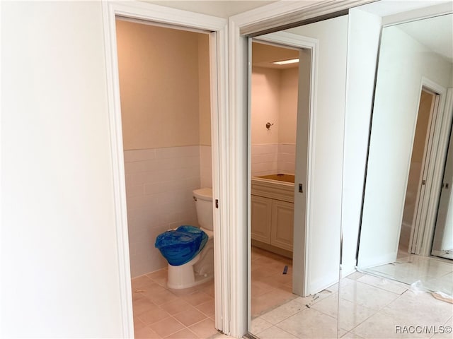 bathroom with tile patterned floors, toilet, and tile walls