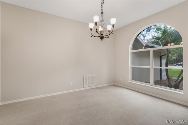 empty room with carpet floors and a notable chandelier