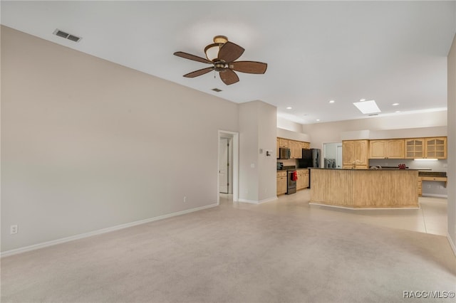 unfurnished living room featuring a skylight and ceiling fan