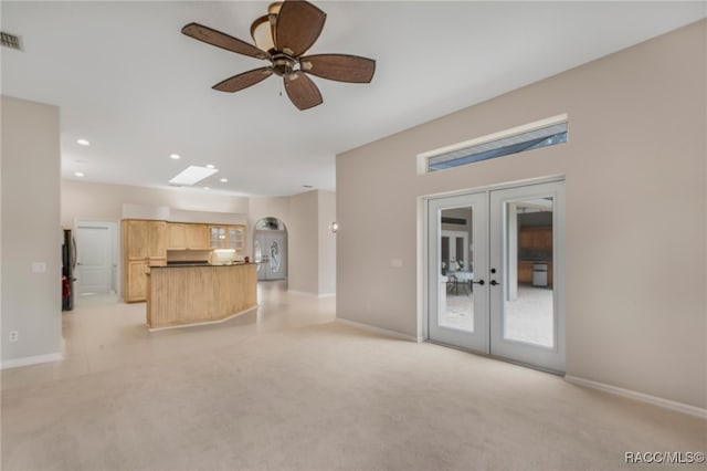 unfurnished living room featuring light carpet, ceiling fan, and french doors