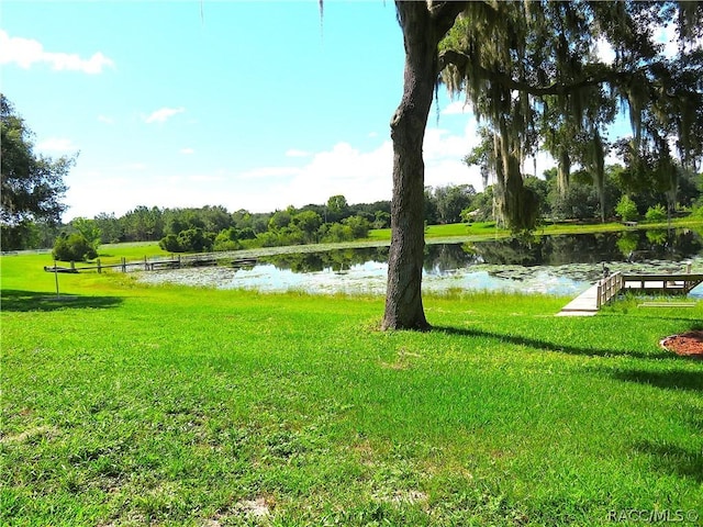 surrounding community with a water view and a yard