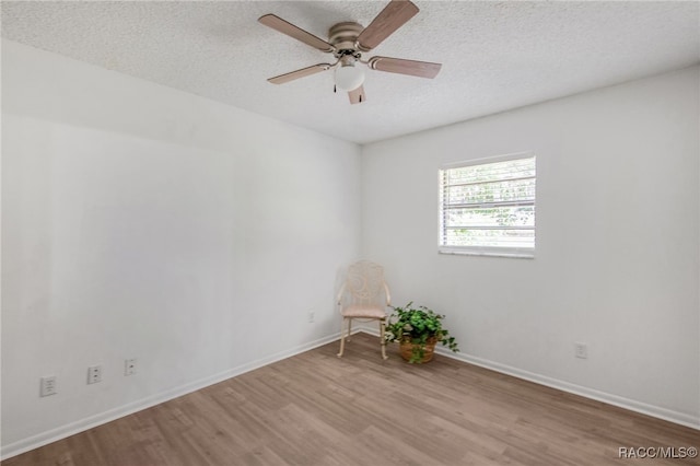 unfurnished room with a textured ceiling, baseboards, wood finished floors, and a ceiling fan