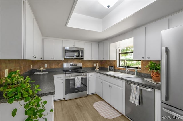 kitchen featuring a sink, dark countertops, stainless steel appliances, white cabinets, and tasteful backsplash