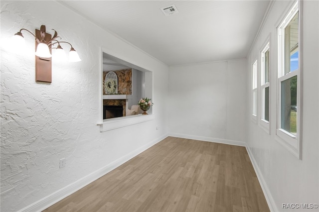 spare room with a large fireplace, visible vents, wood finished floors, and baseboards