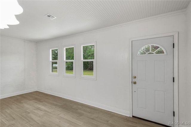 entryway featuring ornamental molding, baseboards, light wood-type flooring, and visible vents