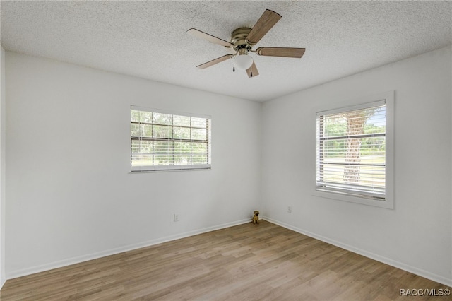 spare room featuring a ceiling fan, baseboards, light wood-type flooring, and a textured ceiling