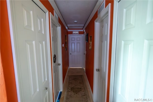 hallway featuring a textured ceiling and ornamental molding